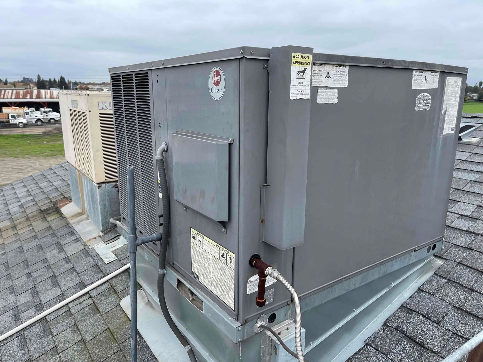 Gray rooftop HVAC unit with vents and access panels on a shingled roof.
