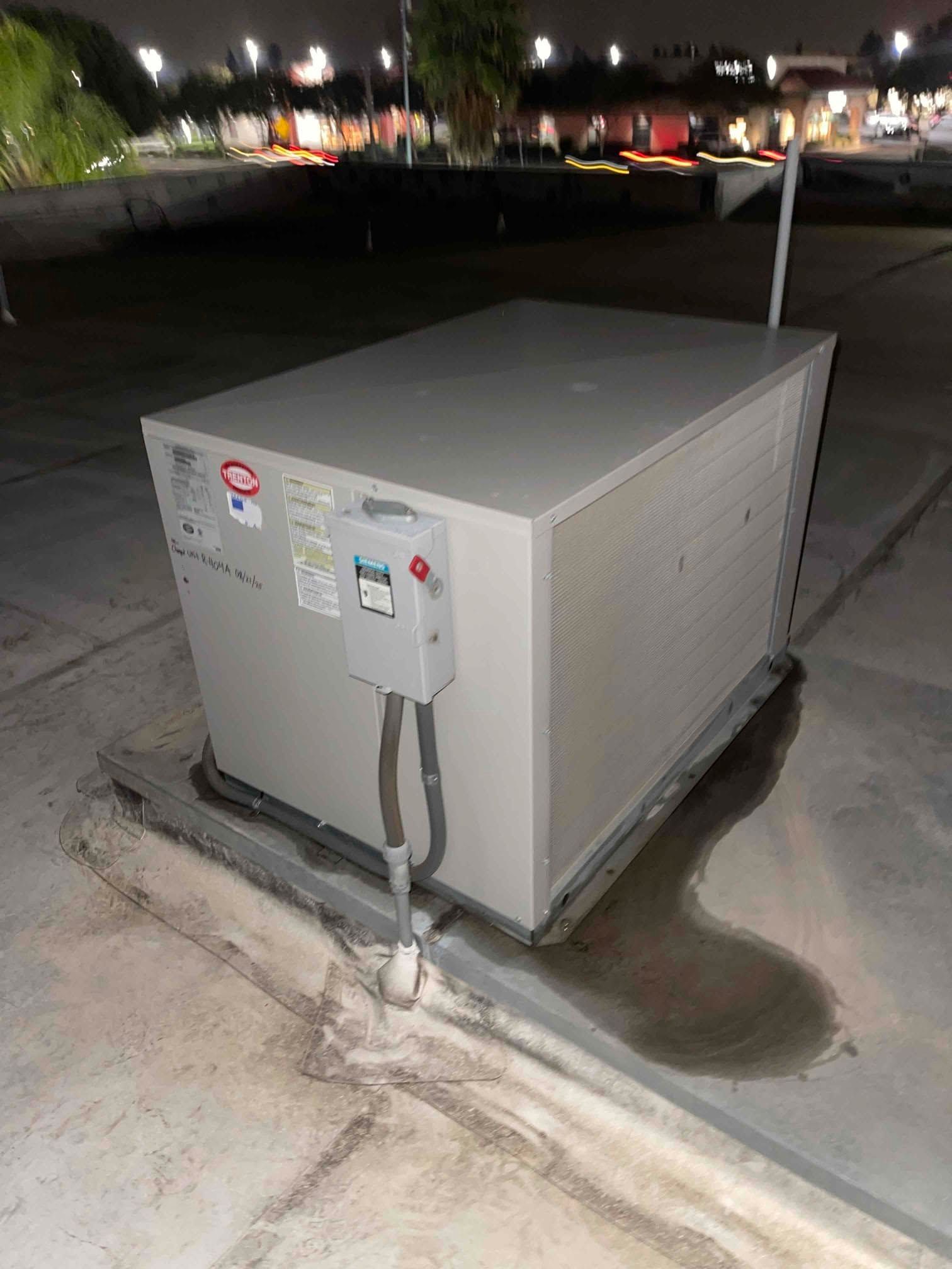 Large gray outdoor electrical unit on a concrete pad at night, with wires and warning labels.