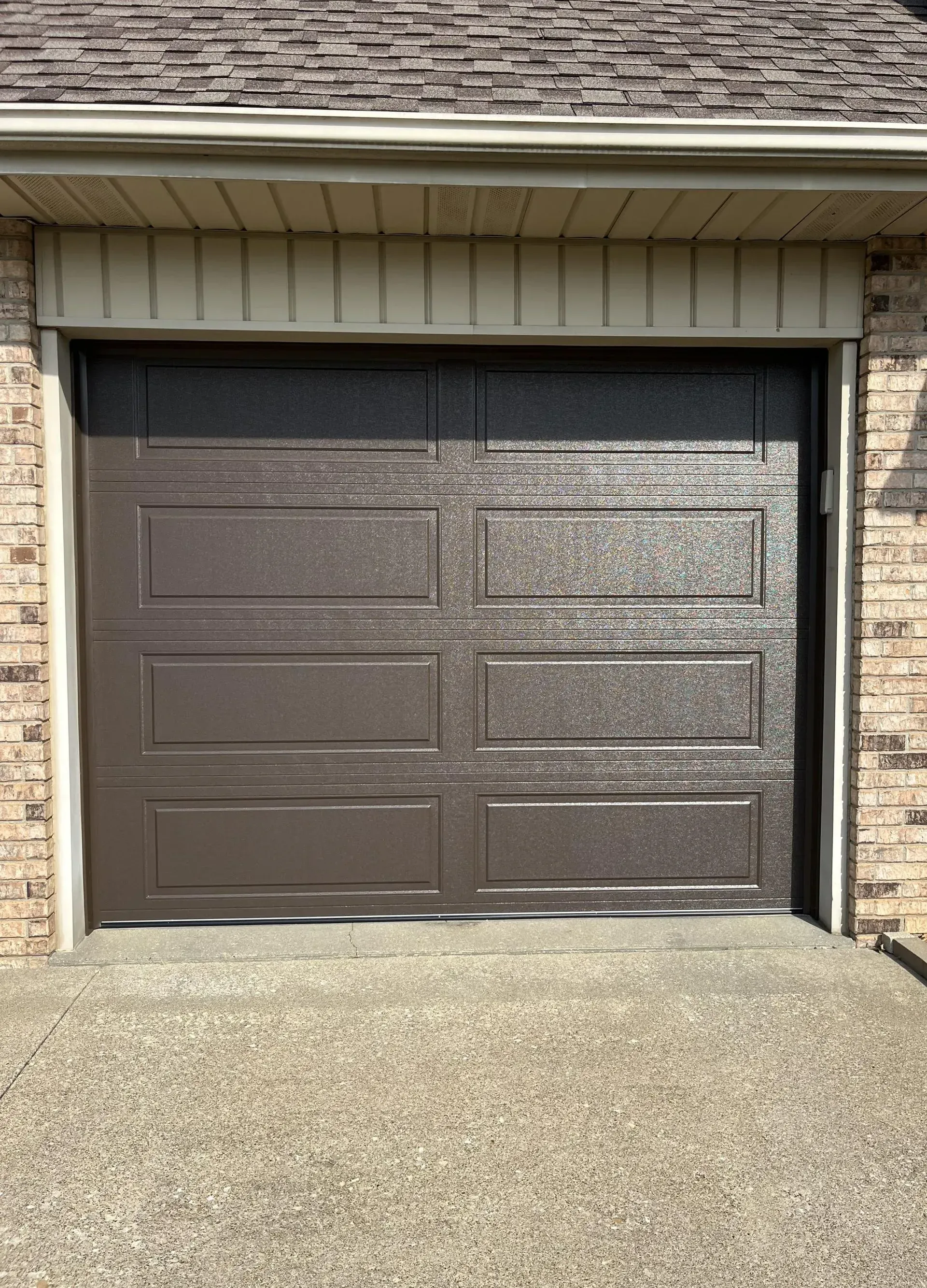Closed brown garage door with brick exterior and concrete driveway