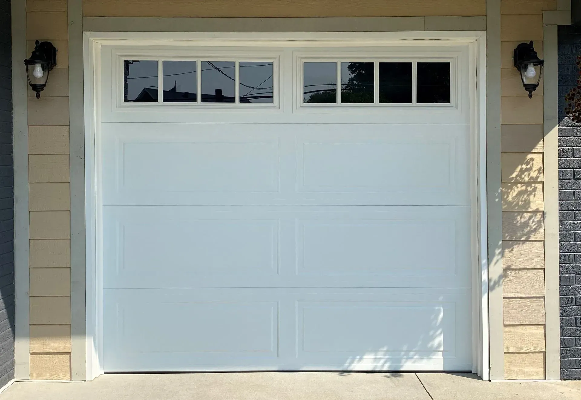 White garage door with small window panes on a house exterior