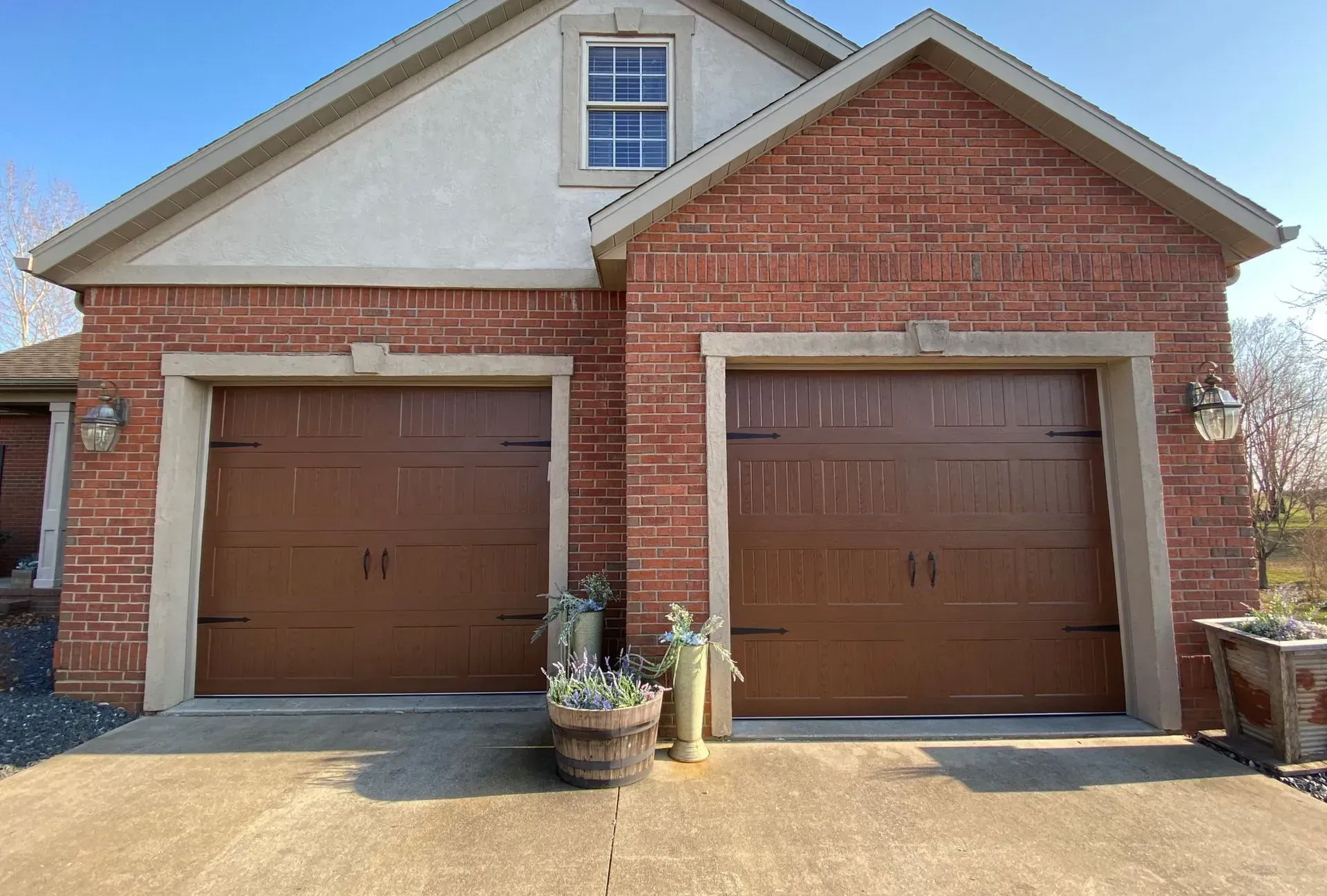 Two-car brick garage with brown doors and white-trimmed gable roof
