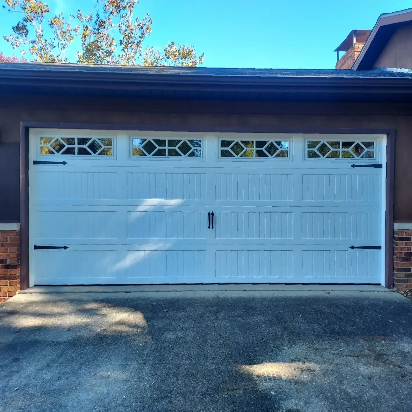 White double garage door with small windows on a brick house, viewed from the driveway.