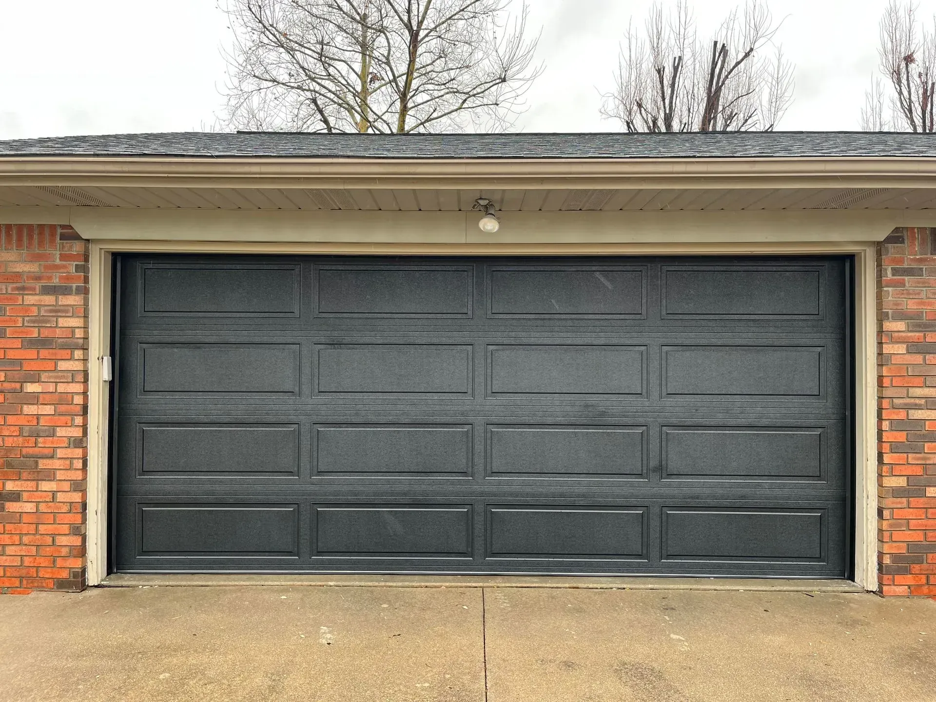 Closed black garage door on a brick house exterior