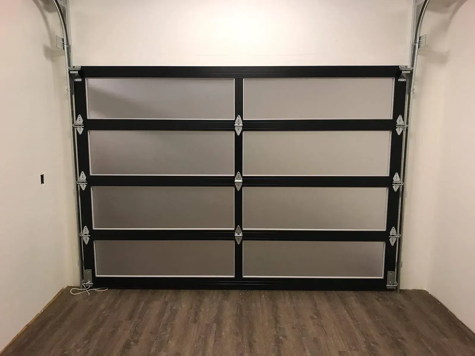 Black garage door with four windows in a clean white garage interior.
