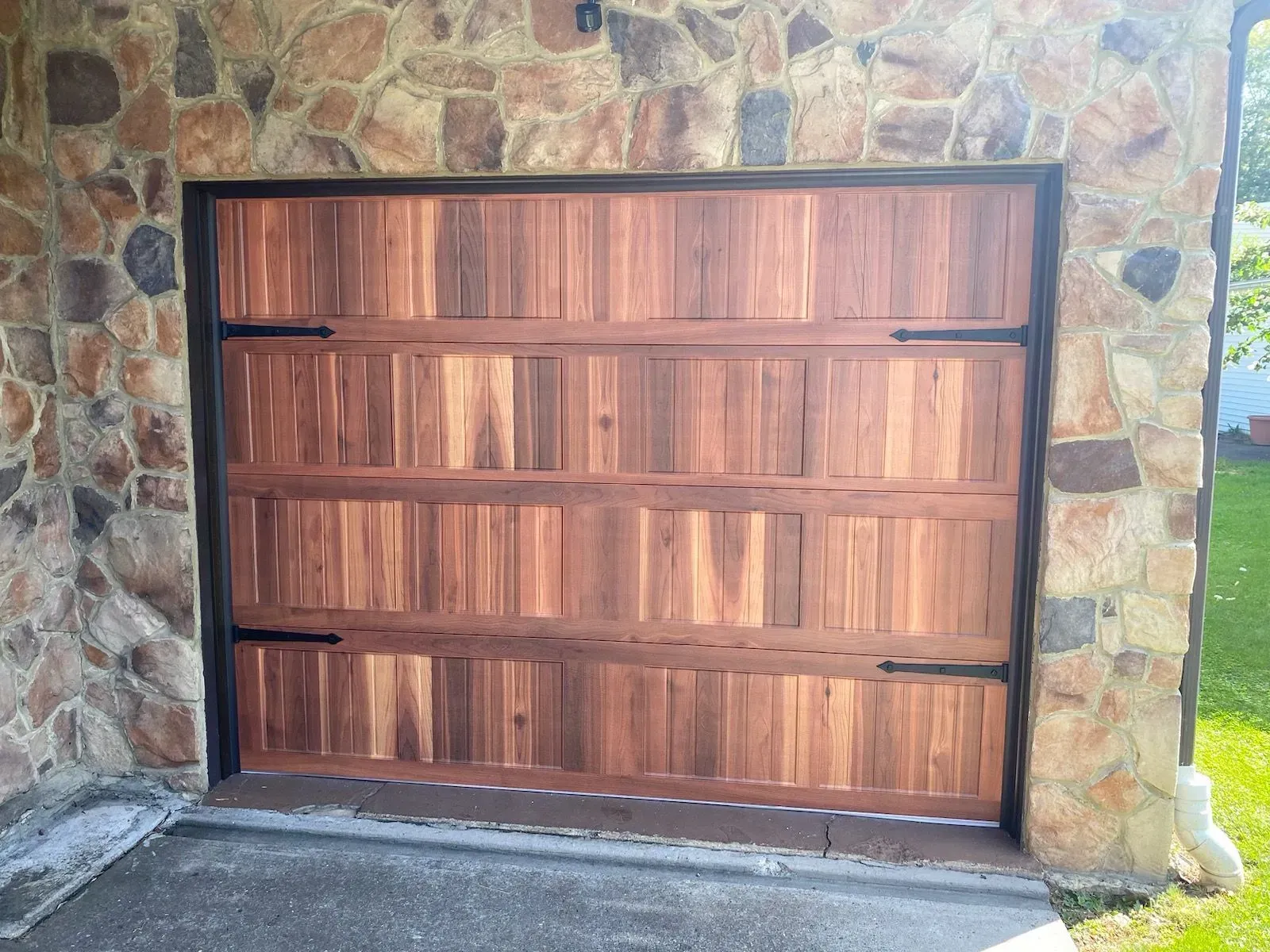 Wooden garage door set in a stone wall, viewed from outside.