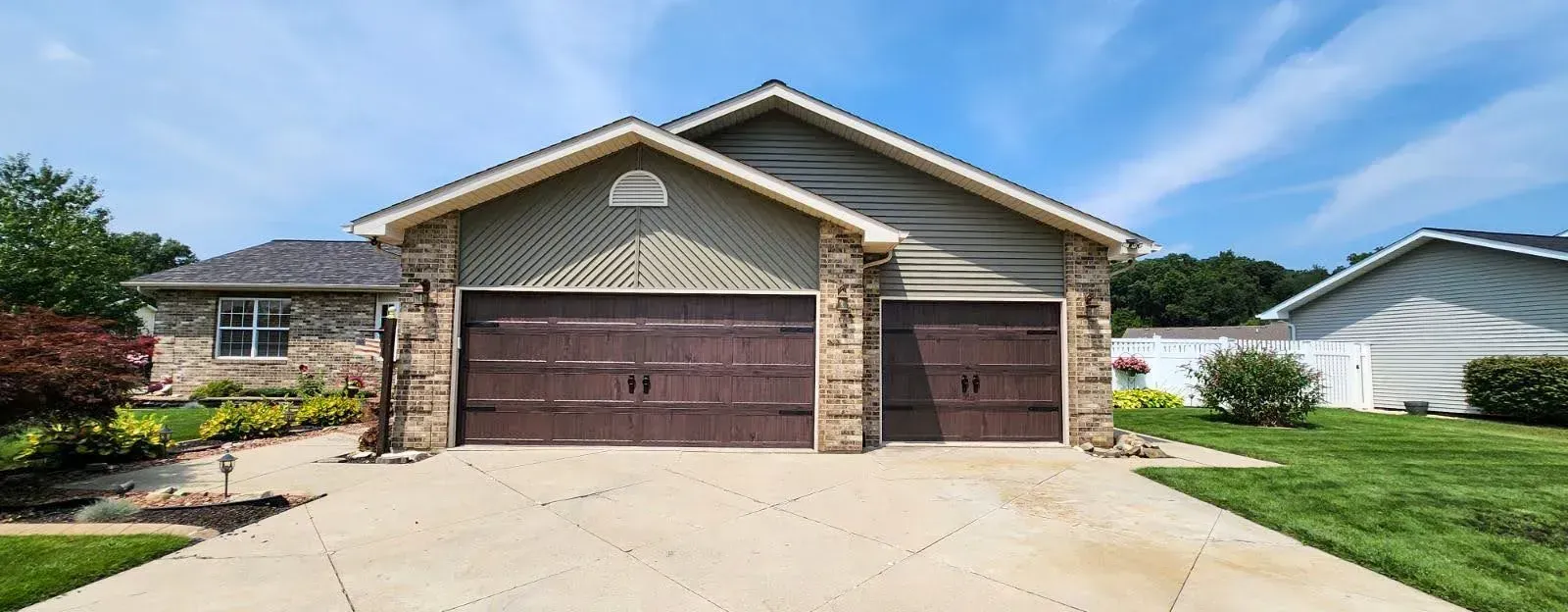 Suburban house with stone accents, three-car garage, and a wide concrete driveway
