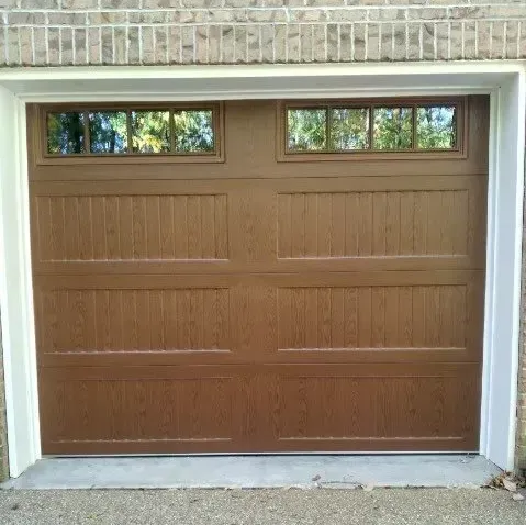 Brown garage door with small windows set in a brick exterior wall