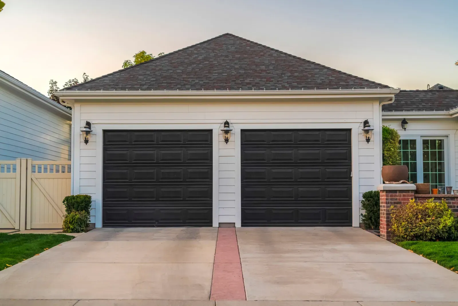 Two-car garage with black doors and white trim, viewed from a driveway in a suburban home.