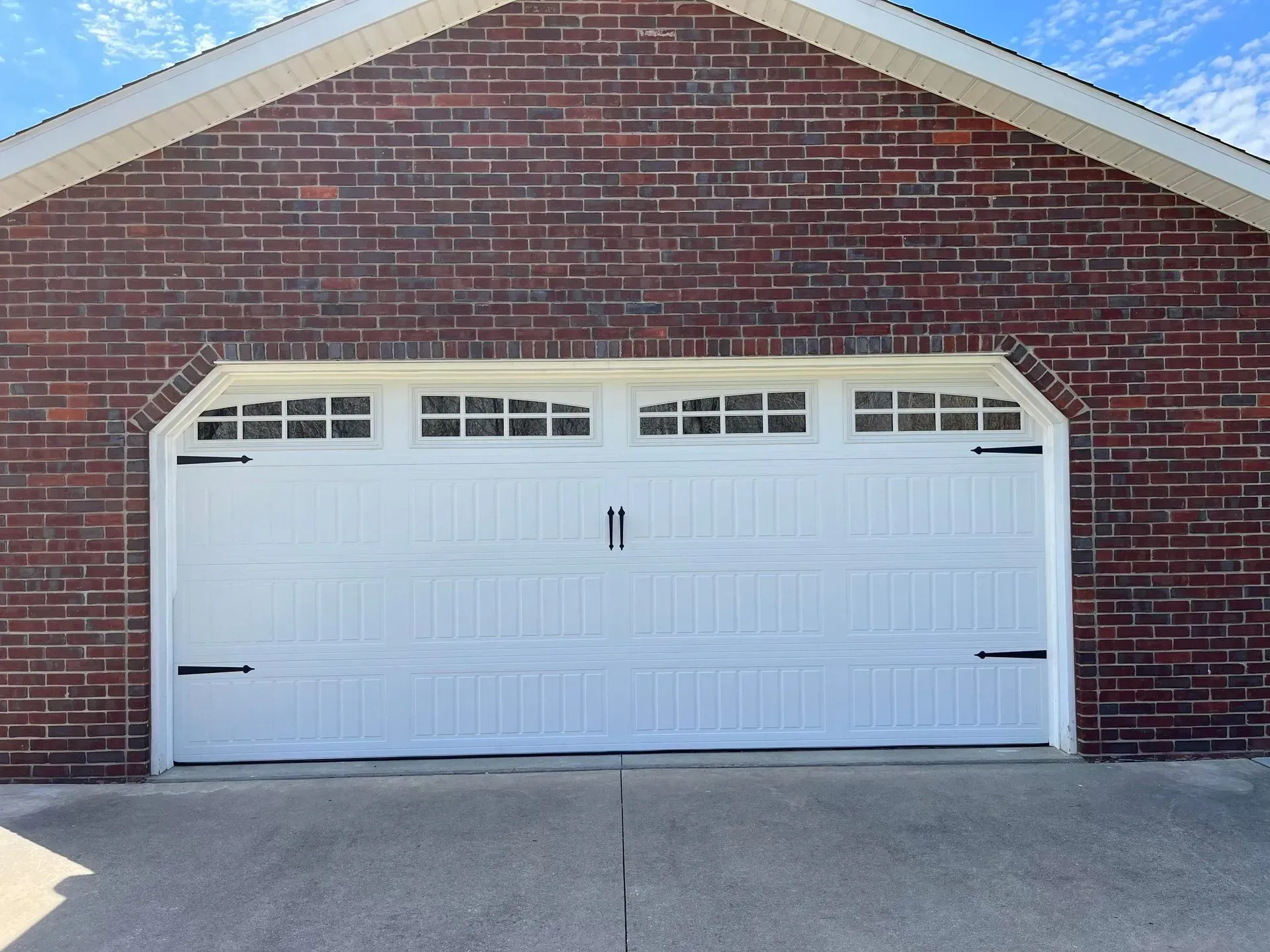 Brick house with white double garage door and driveway