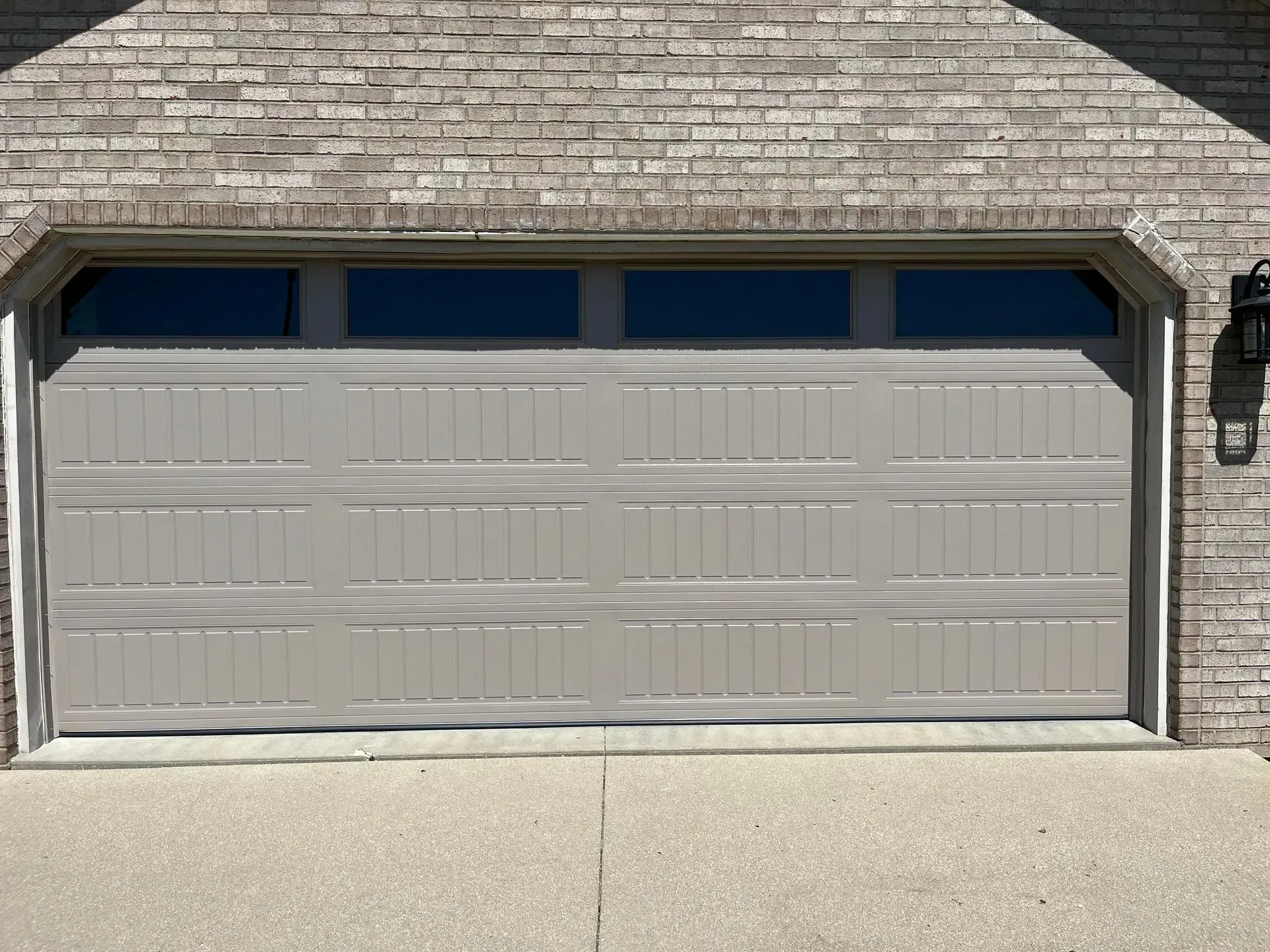 Closed beige garage door on a brick house facade.