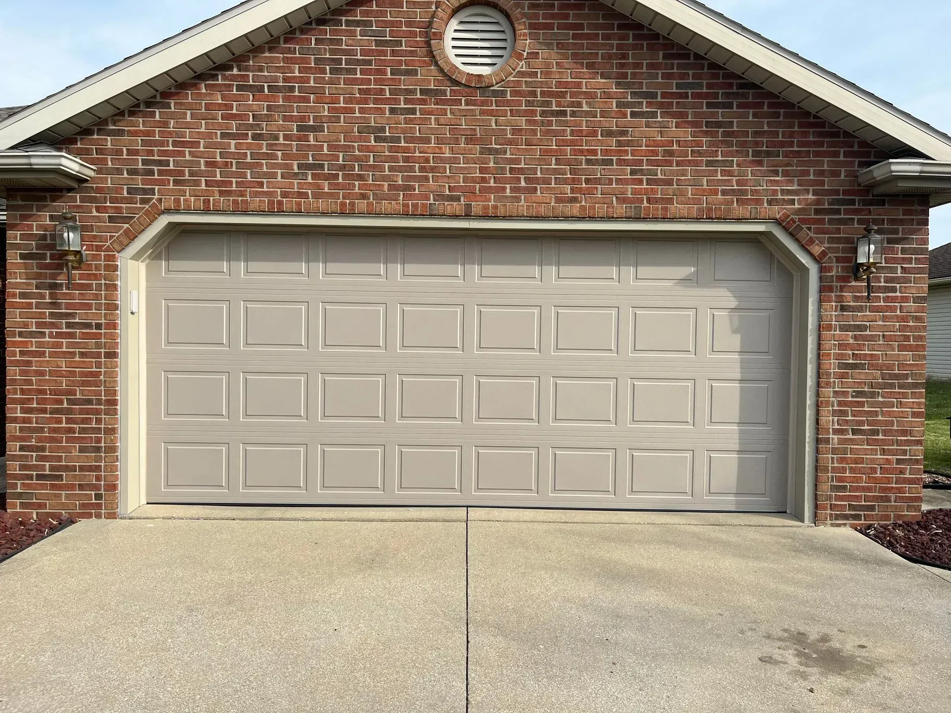 Brick house front with a closed beige garage door and concrete driveway
