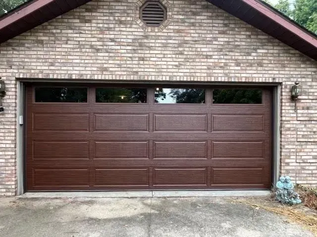 Brown two-car garage door on a brick house exterior