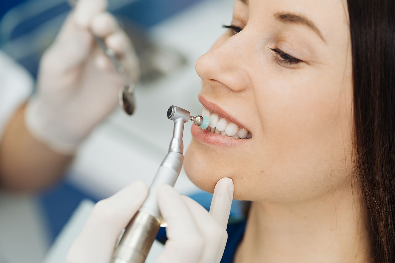A woman receives a dental cleaning from a dentist, inside a dentist's office. A woman receives a dental cleaning from a dentist, inside a dentist's office.