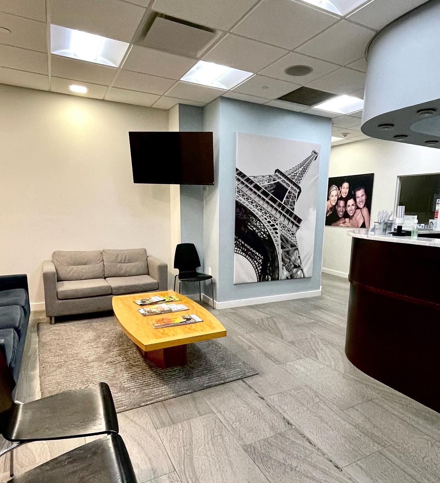 Reception area with couch, coffee table, chairs, Eiffel Tower art, and reception desk.