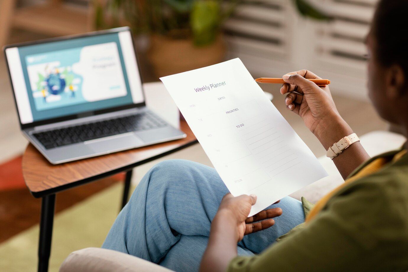 A woman is sitting on a couch holding a piece of paper and a pen.