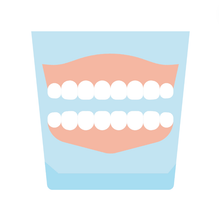 A pair of dentures in a glass on a white background.