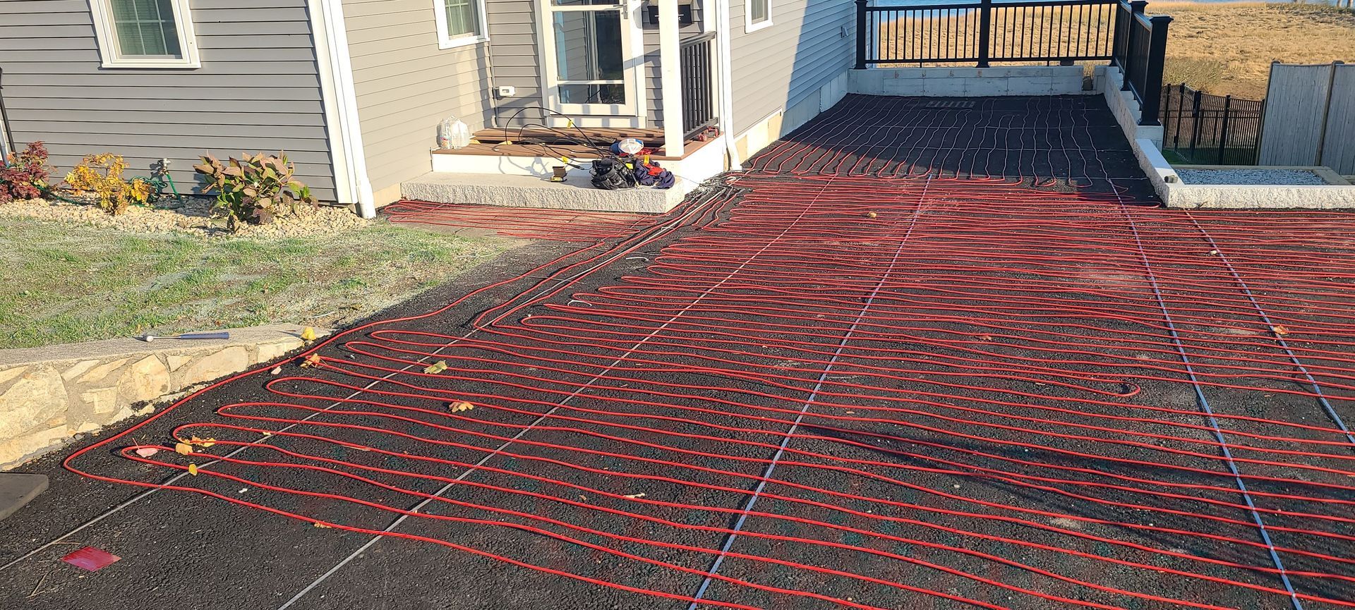 Red mesh tarp covering a sloped driveway beside a house entrance and porch steps.