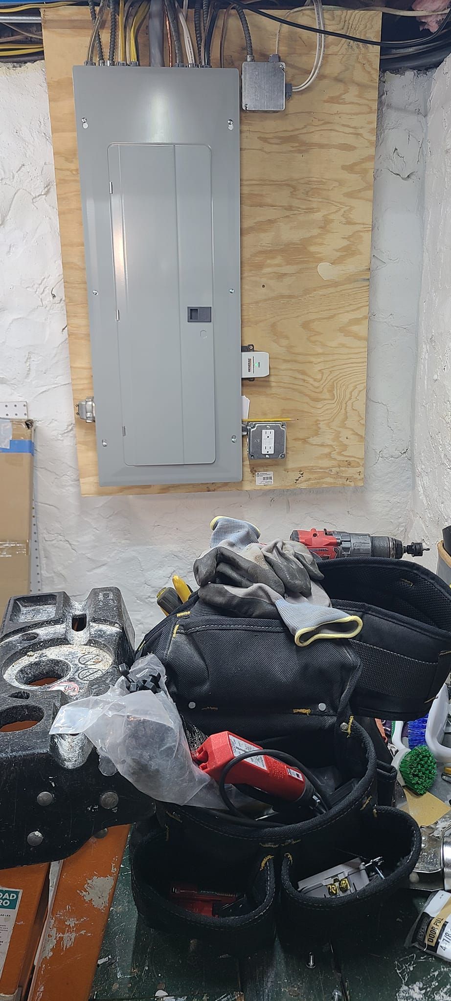 Basement utility area with electrical panel, exposed insulation, and a heap of trash bags and debris.