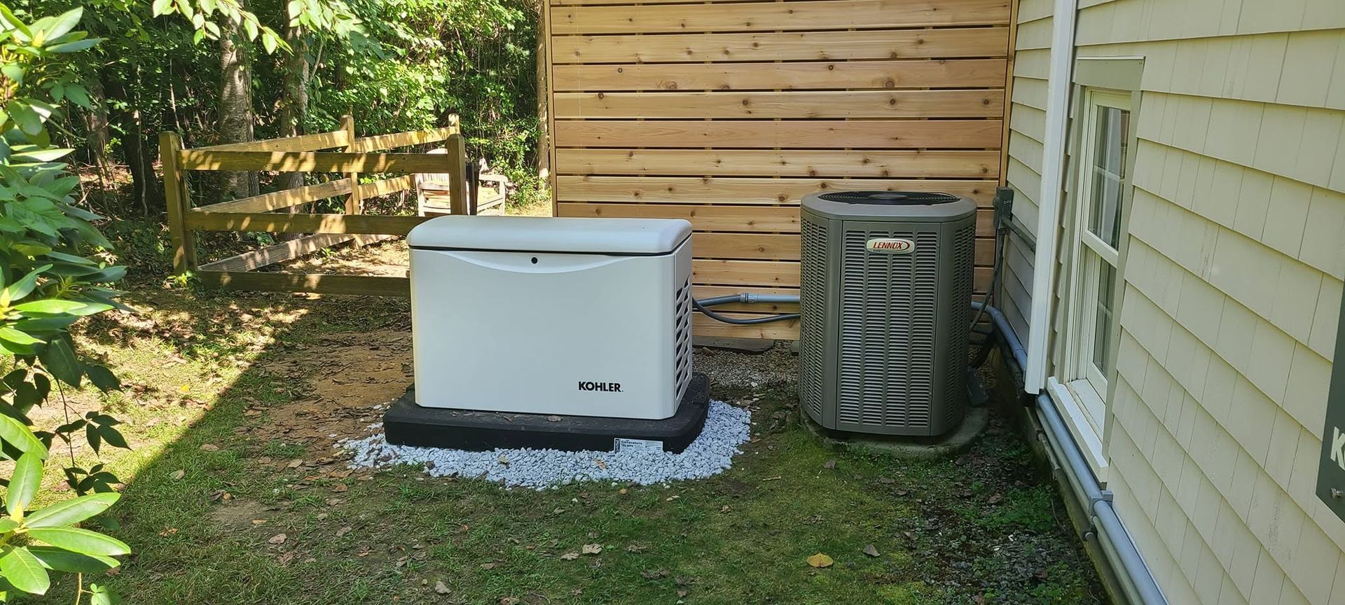 Outdoor side yard with a white storage bin, air conditioner unit, and a wooden fence backdrop