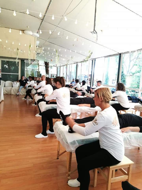 Un gruppo di persone è seduto su lettini per massaggi in una stanza.