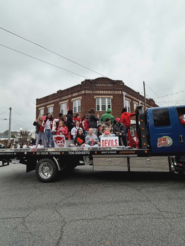 Students on a flatbed truck, holding signs. Building in the background. Overcast sky.