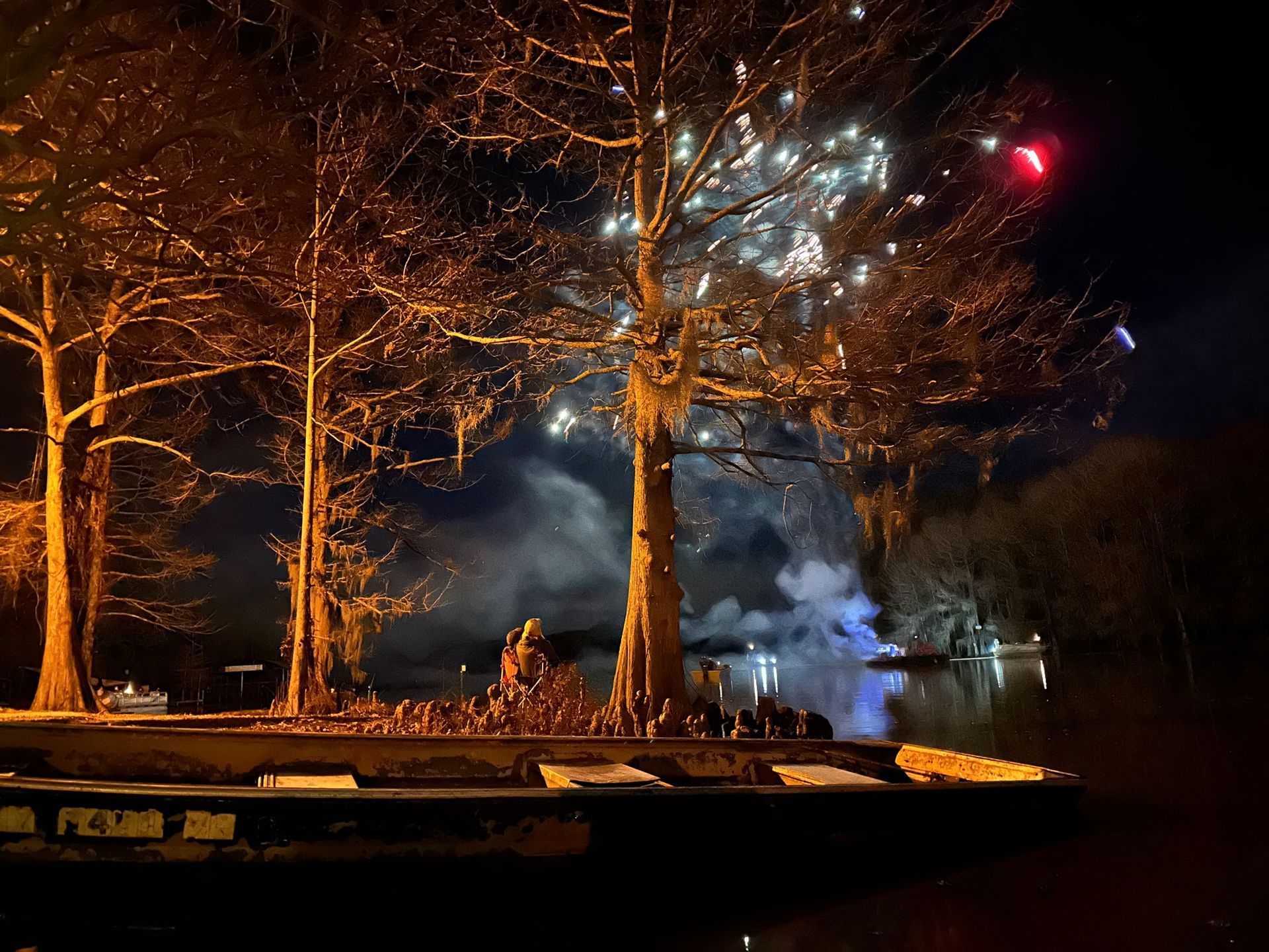 Fireworks are being displayed in the night sky over a body of water