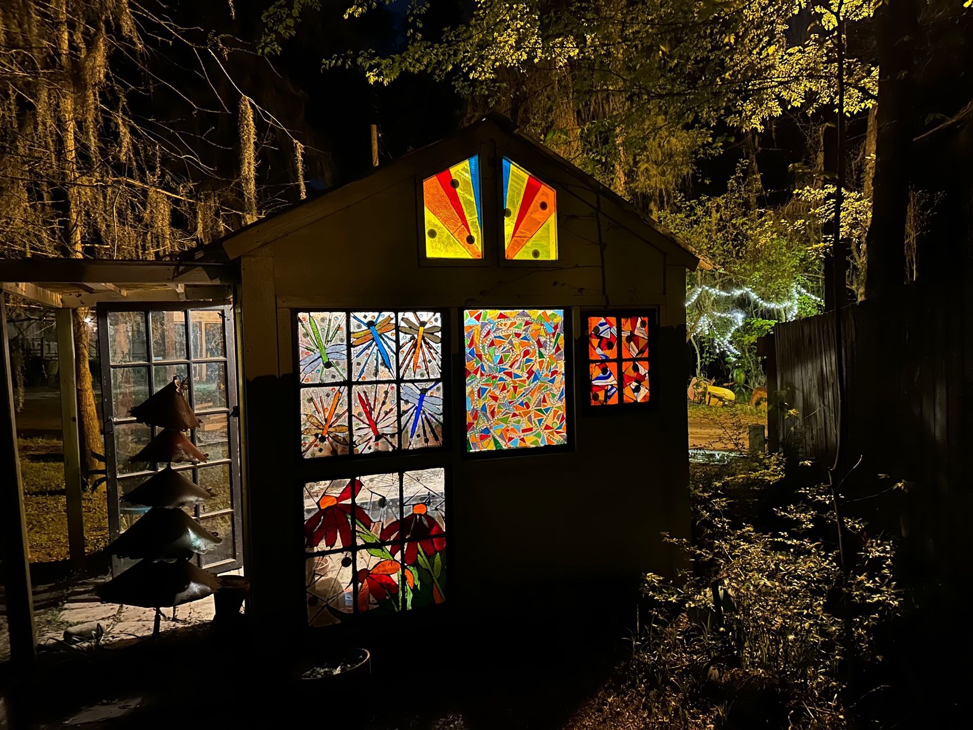 A shed with stained glass windows is lit up at night.