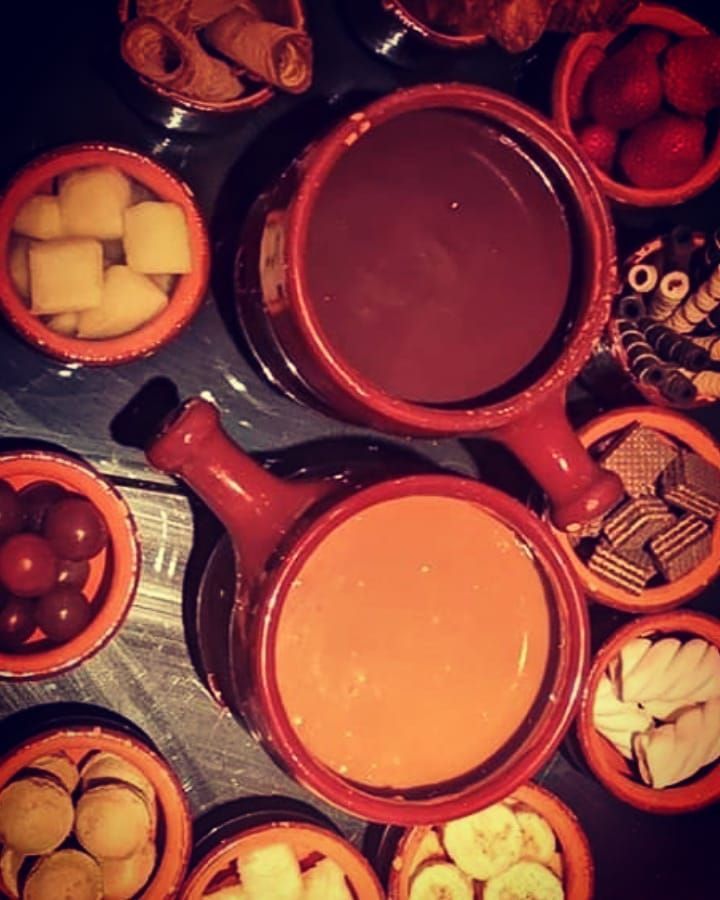 Uma mesa coberta com tigelas de comida, incluindo fondue de chocolate Gramado Serra Gaúcha