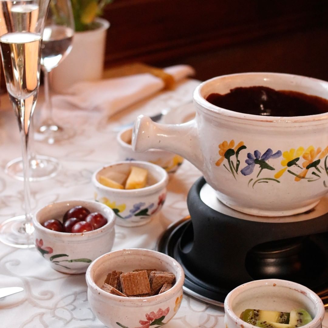 Um vaso de fondue com flores sobre uma mesa Gramado Serra Gaúcha