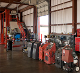 Interior of an auto repair shop with various pieces of red and black machinery, tools, and a metal staircase.
