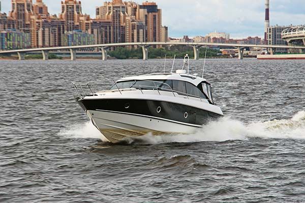 A boat is floating on top of a body of water with a bridge in the background.