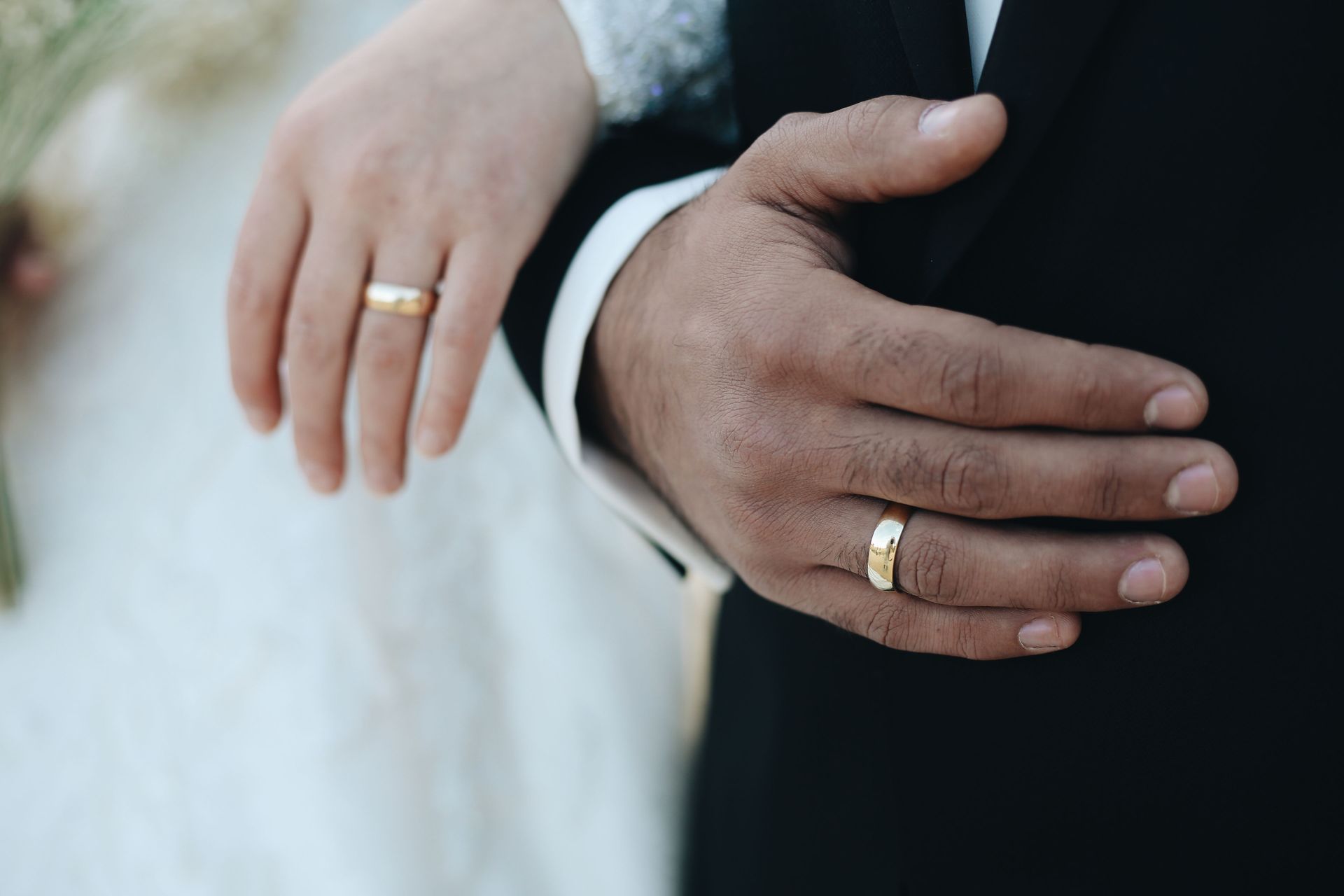 Newly married North Texas couple wearing gold wedding rings, a reminder to update auto, home and life insurance