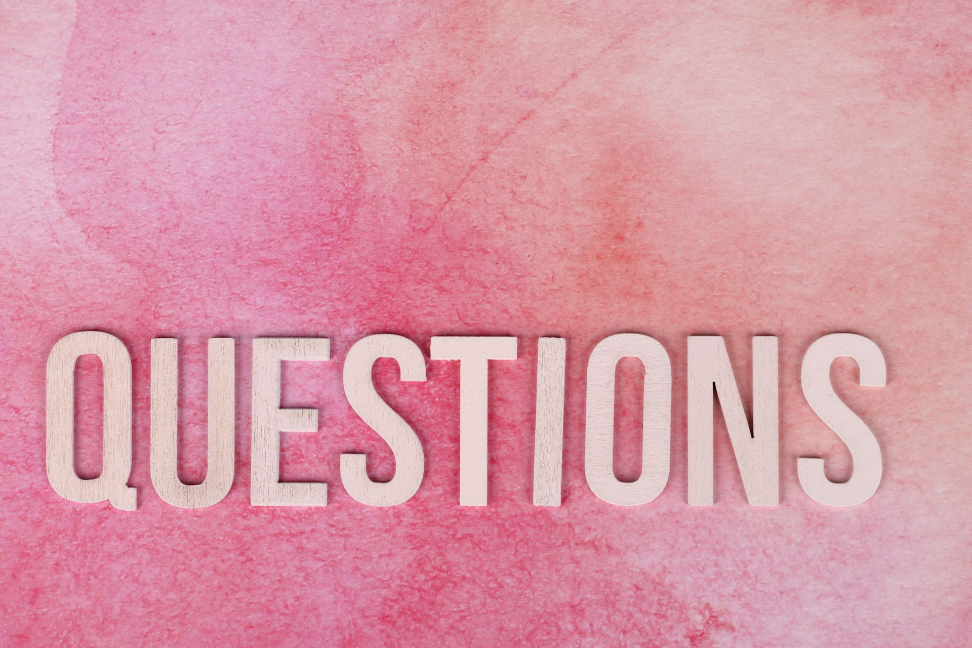 Pink watercolor background with the word “QUESTIONS” in large white letters