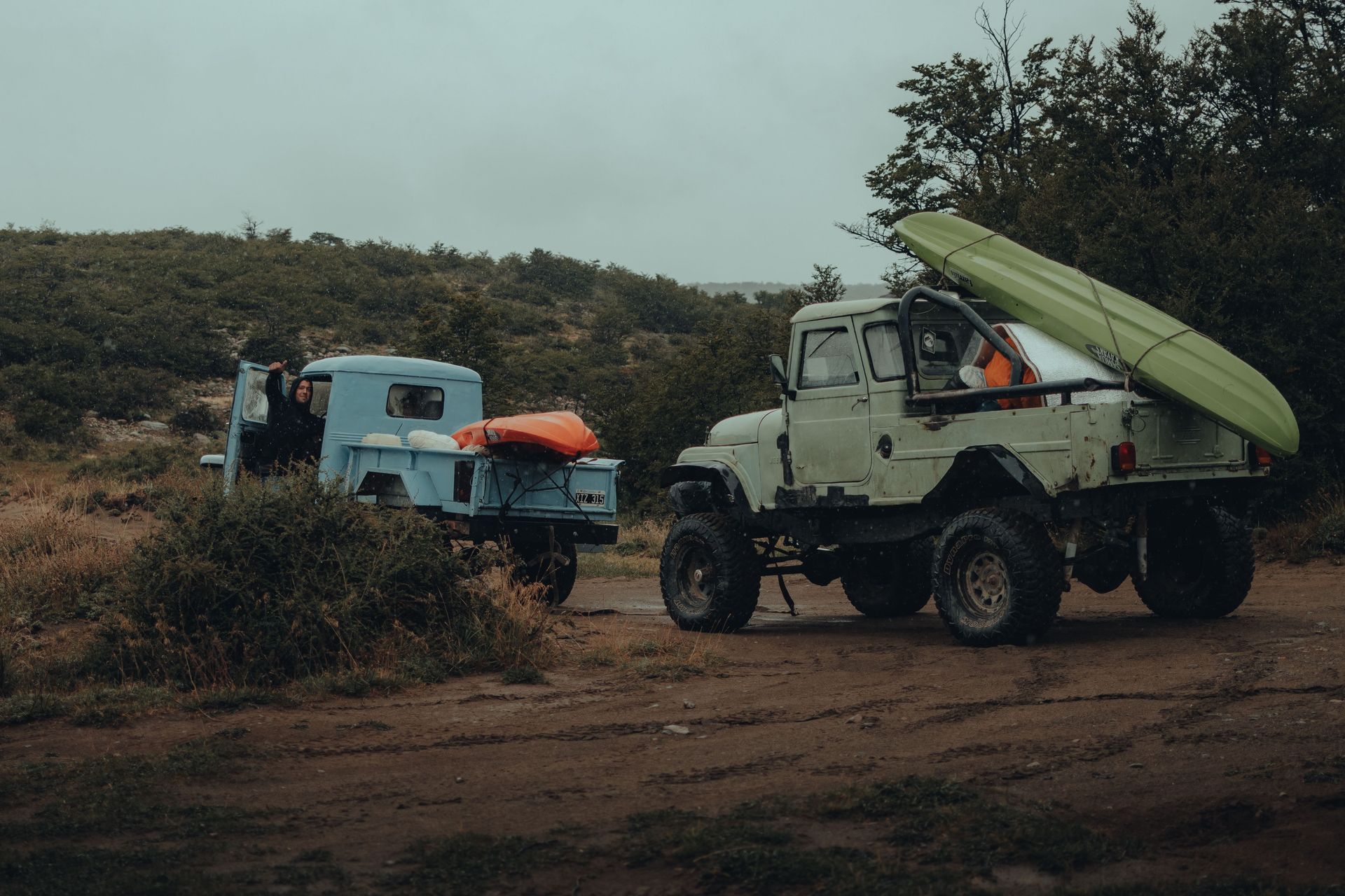 Gear-loaded pickups on a dirt track, the kind of seasonal trip a comprehensive-only storage policy has to plan around