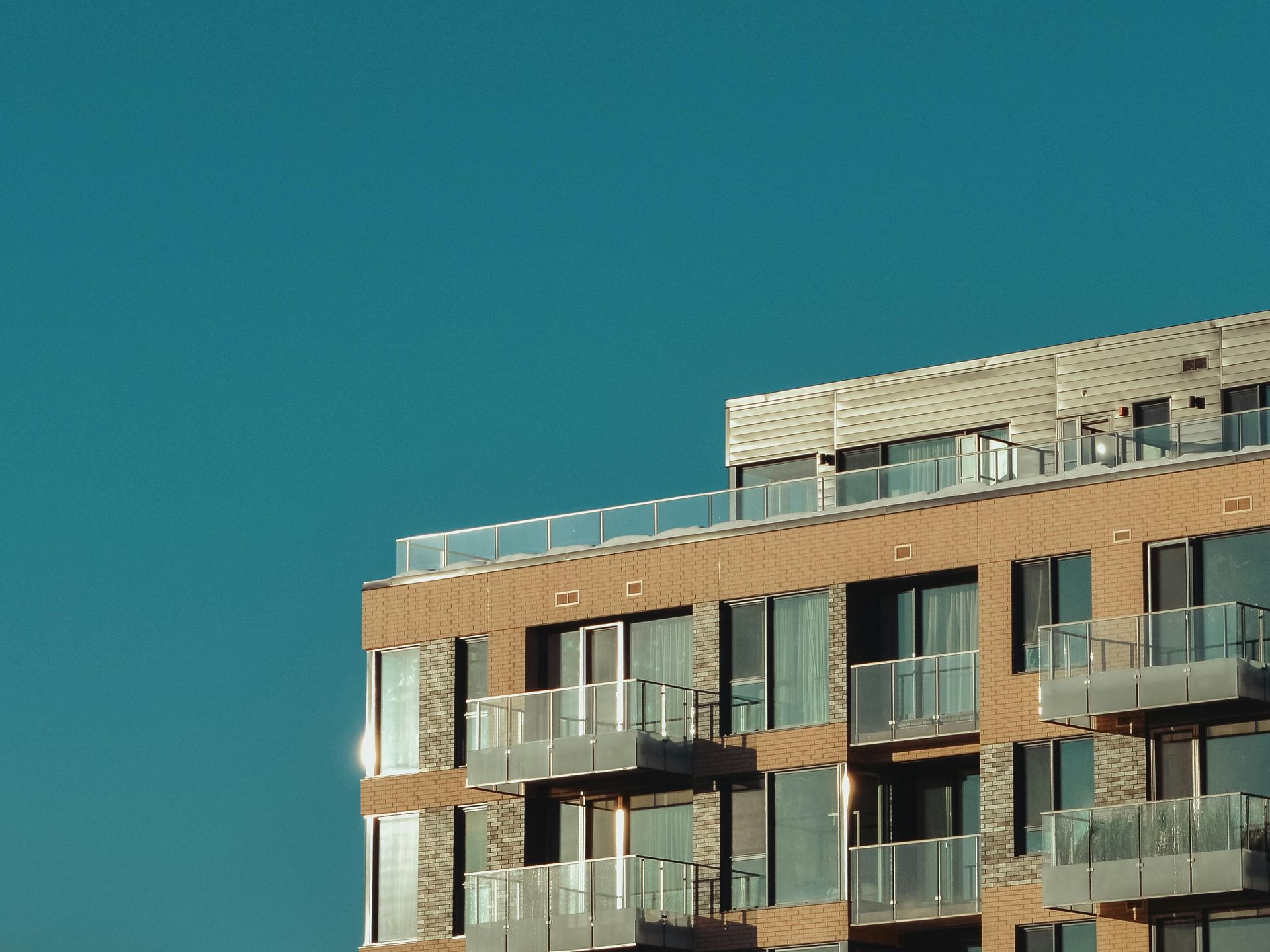 Modern apartment building with glass balconies against a clear blue sky