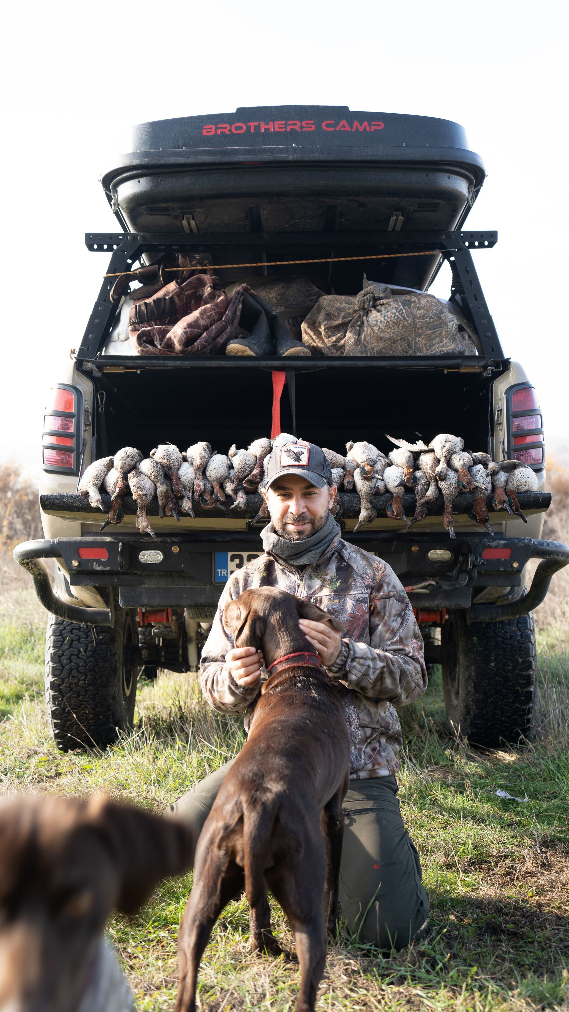 Hunter in camo with his bird dog at the truck after a dove hunt, gear loaded for the drive home