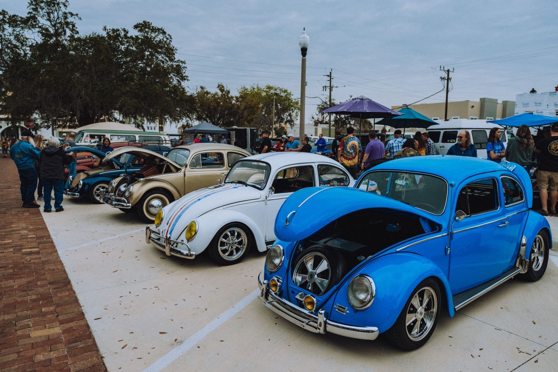 A restored classic car with polished chrome and whitewall tires parked at an outdoor summer car show