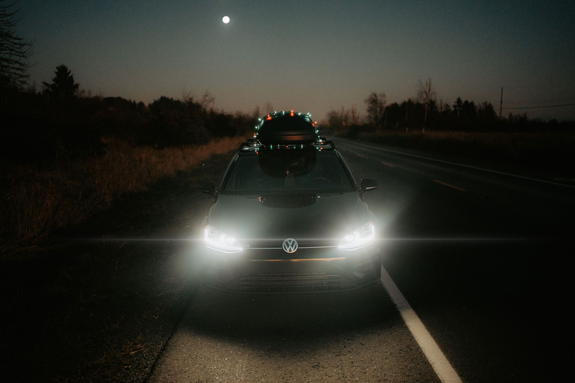 Headlights of a vehicle on a dark two-lane Texas farm road at dusk, prime hours for deer in fall