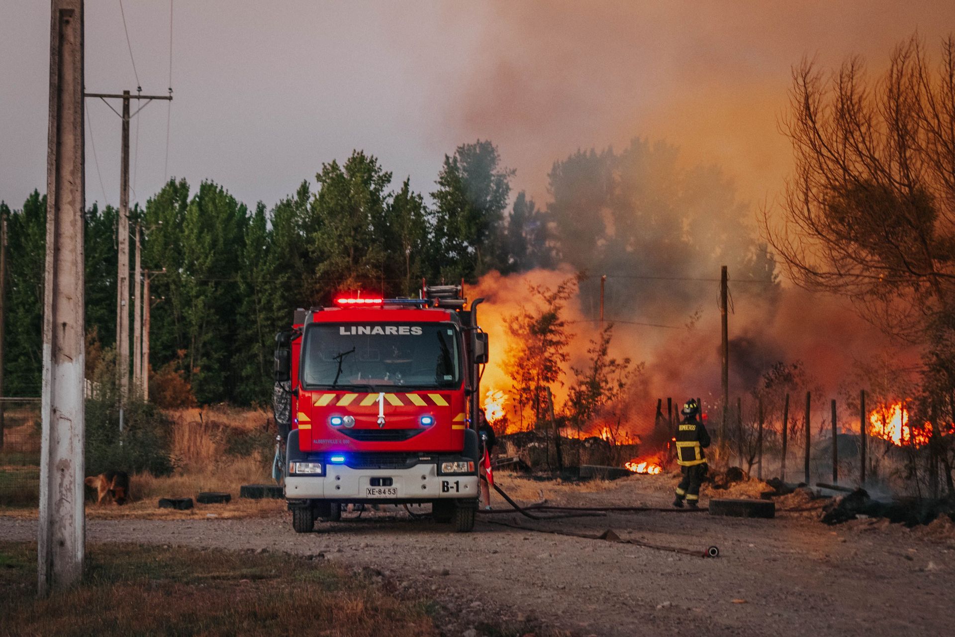 Fire engine crew fighting a grass fire near rural property fence line during a North Texas summer burn ban