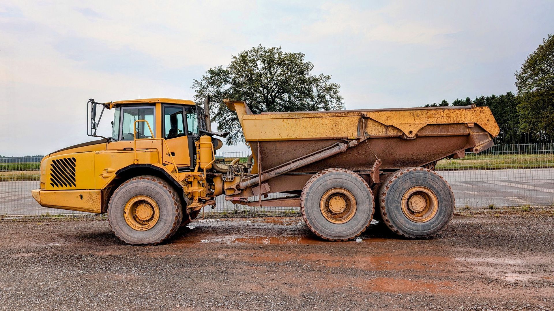 Yellow articulated dump truck parked on a gravel jobsite yard of the kind used for aggregate hauling