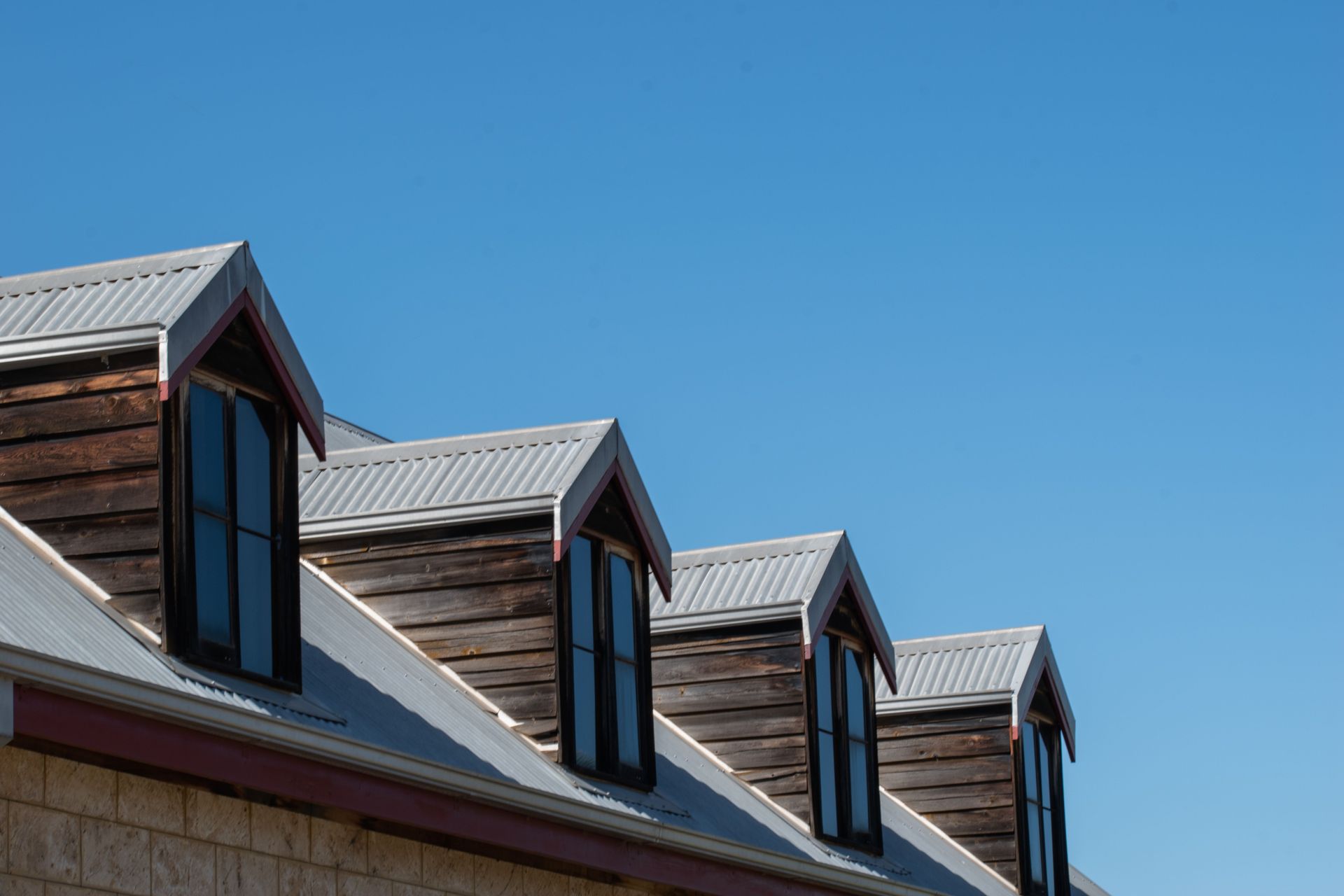 Row of dormer windows on a sloped roof against a clear blue sky