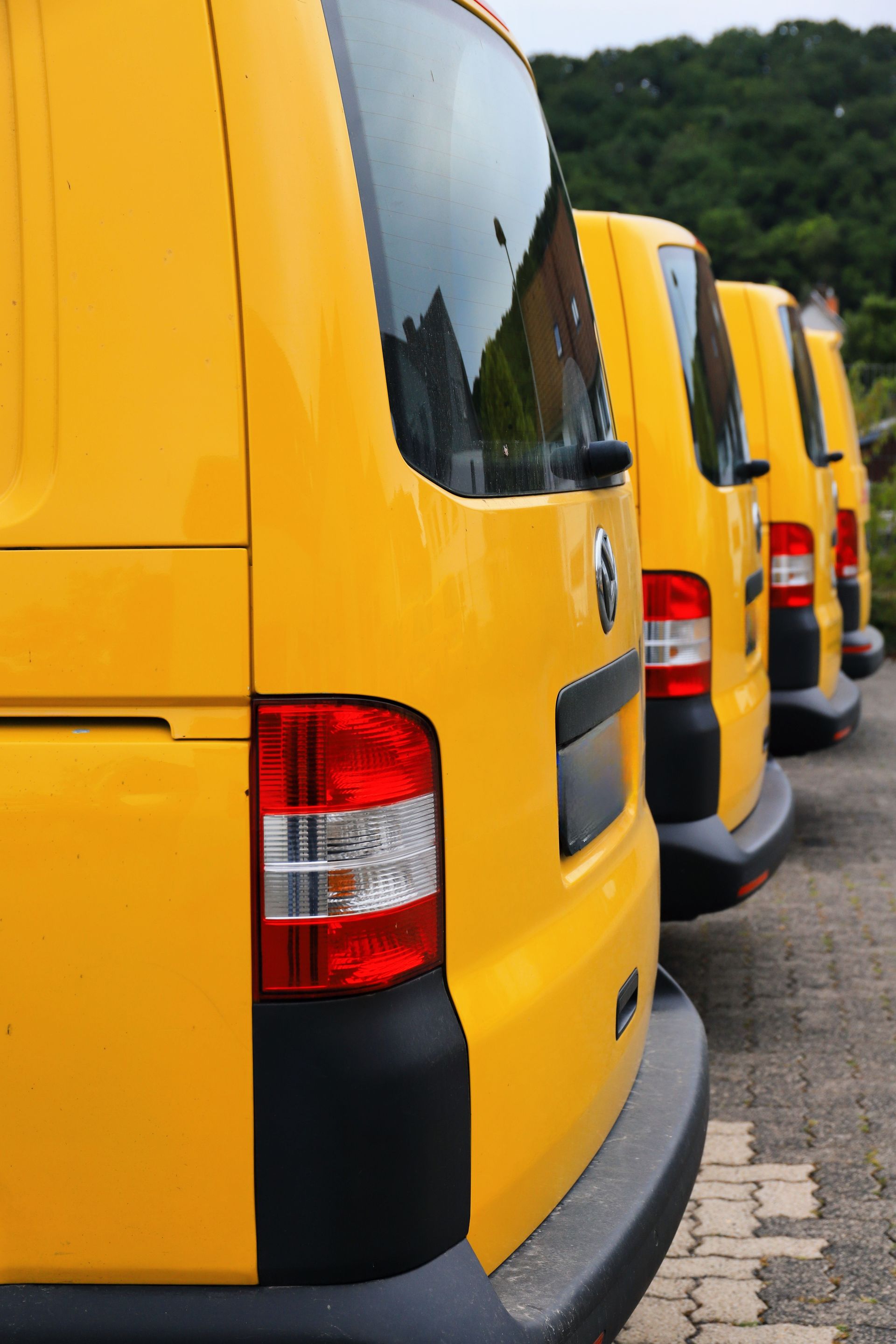Row of yellow delivery vans parked side by side along a curb
