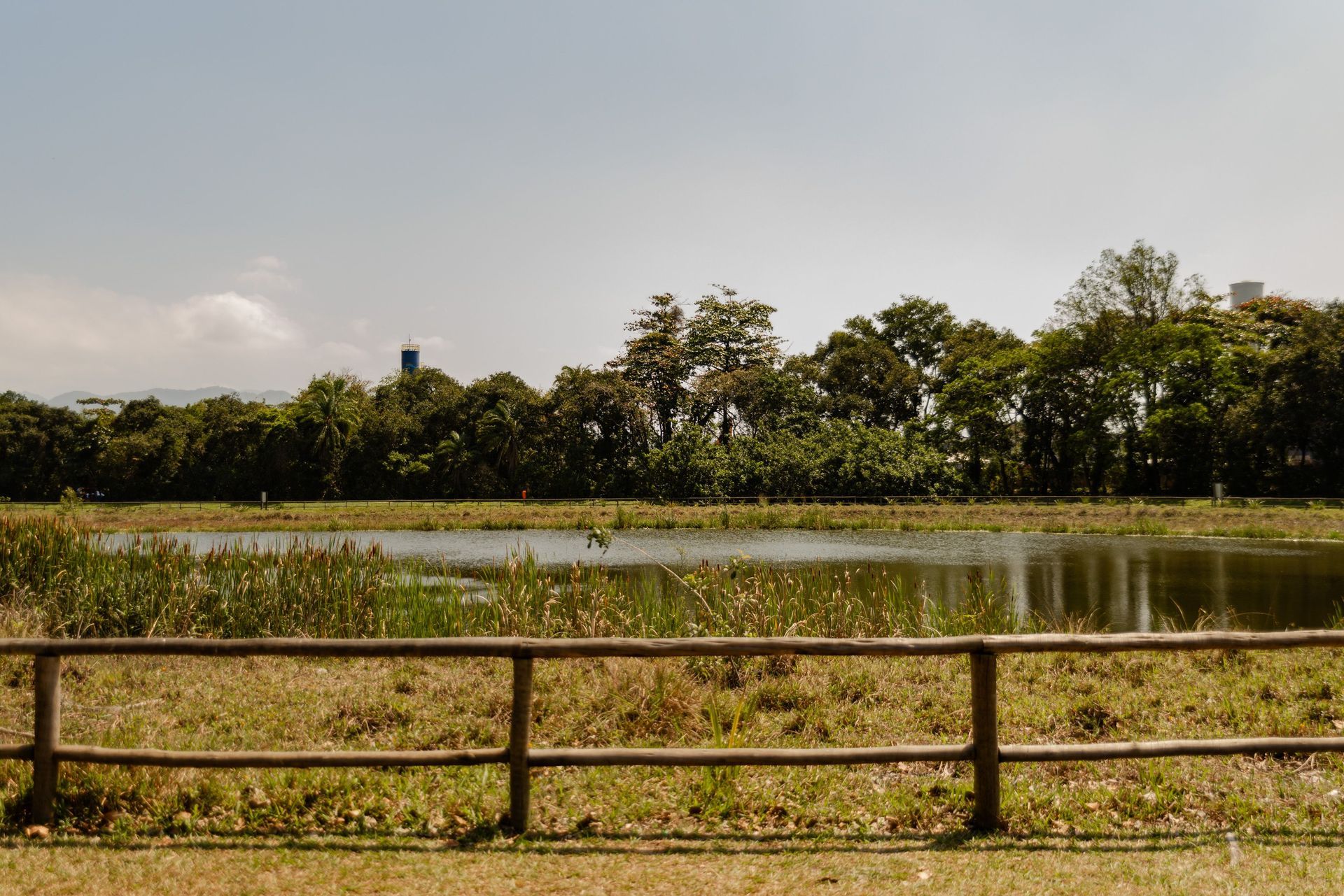 Open rural acreage with a pond and a wooden fence line, the kind of lot a custom home is built on