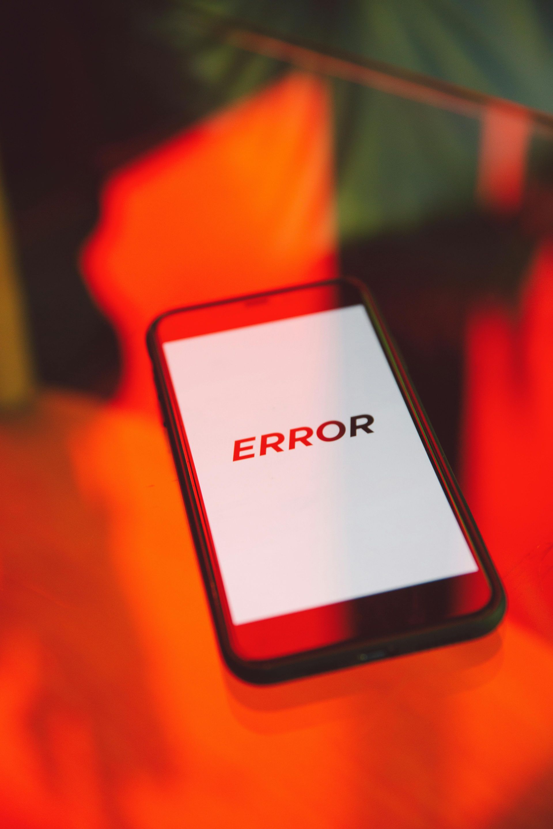 Smartphone on a red-orange surface displaying “ERROR” on a white screen