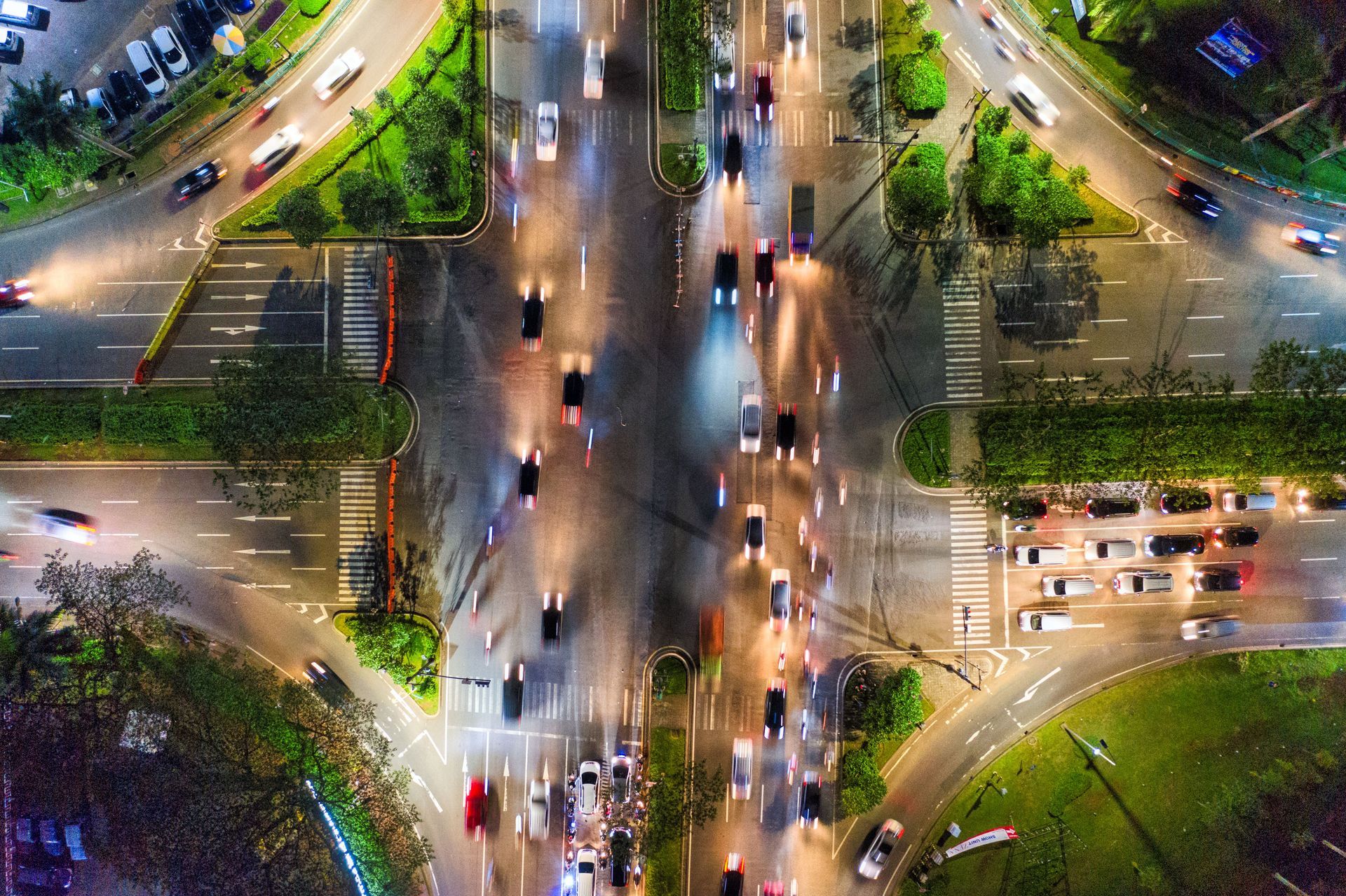 Aerial view of a busy city intersection with moving cars and streetlights at night.