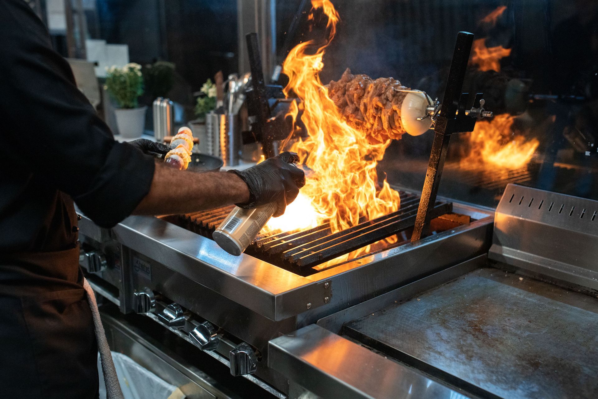 Cook working a flaming grill in a commercial kitchen, where auto, property, and liability risks share one rig