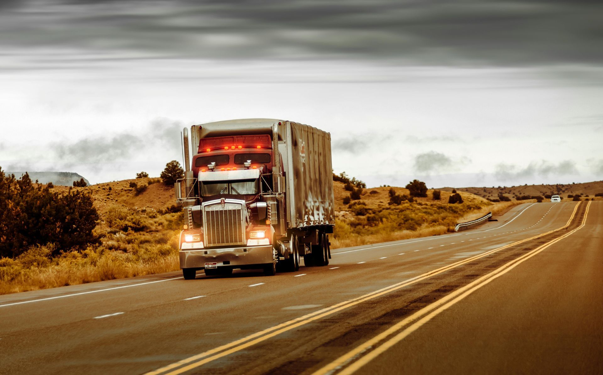 Semi-truck driving on a rural highway under cloudy skies