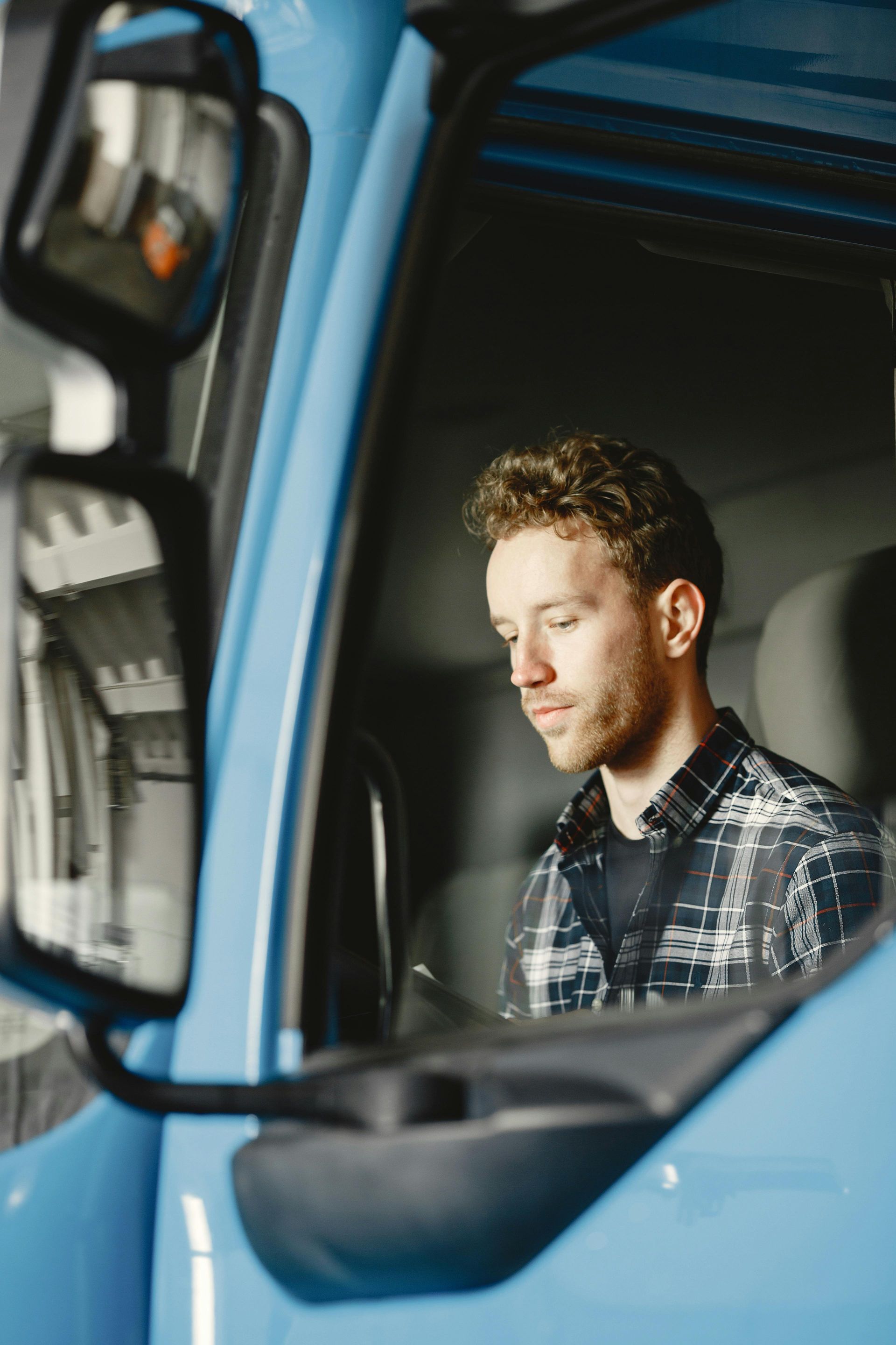 Man sitting in the driver’s seat of a blue truck, looking down pensively