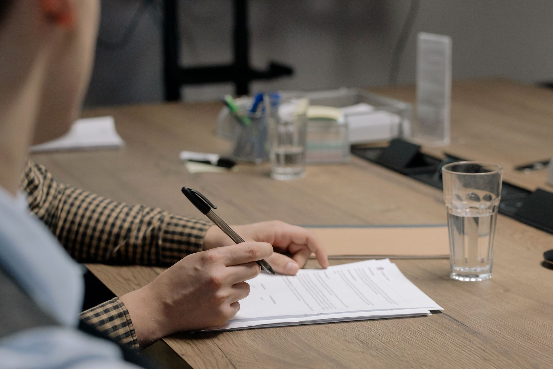 Business owner signing paperwork at a wooden conference table during a buy-sell agreement review