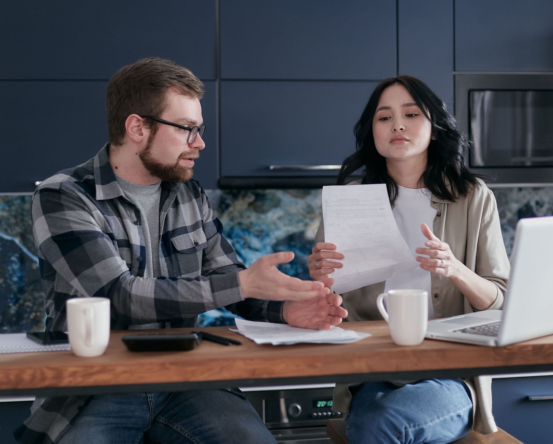 A couple at a kitchen table reading a printed letter together, the kind of servicer notice that follows a lapsed home policy